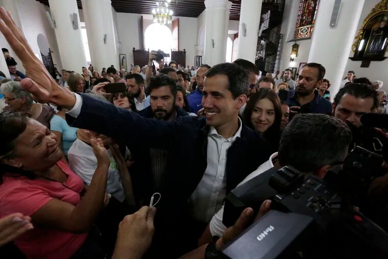 Opposition National Assembly leader Juan Guaido, who declared himself interim president, greets supporters as he arrives to attend Mass at a church in Caracas, Venezuela, Sunday, Jan. 27, 2019.  Guaido says he is acting in accordance with two articles of the constitution that give the National Assembly president the right to hold power temporarily and call new elections. (AP Photo/Fernando Llano)