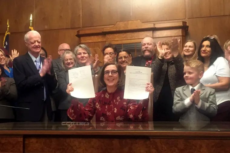 Oregon Gov. Kate Brown holds up a signed rent control bill on Thursday, Feb. 28, 2019, at the State Capitol in Salem, Ore. The state is now the first in the nation to impose mandatory rent control. Landlords would only be allowed to raise rent a limited amount once per year under the bill, and it is meant to address a housing crisis that has touched every corner of the state. (AP Photo/Sarah Zimmerman)