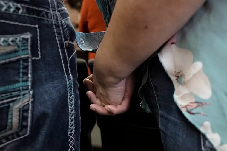 Guadalupe Rodriguez Pino, right, holds the hand of her husband Gerardo Meza Vargas as they attend a Sunday church service, Sunday, Dec. 17, 2023, in Fort Morgan, Colo. The couple, who have four U.S.-born children, are in the process of getting legal immigration status. (AP Photo/Julio Cortez)