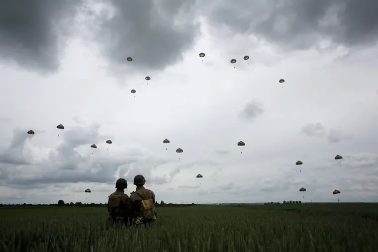 WWII enthusiasts watch French and British parachutists jumping during a commemorative parachute jump over Sannerville, Normandy, Wednesday, June 5, 2019. Extensive commemorations are being held in the U.K. and France to honor the nearly 160,000 troops from Britain, the United States, Canada and other nations who landed in Normandy on June 6, 1944 in history's biggest amphibious invasion.