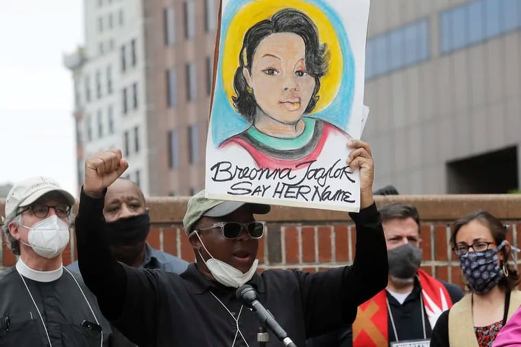 In this June 9 photo, Kevin Peterson, center, founder and executive director of the New Democracy Coalition, displays a placard showing Breonna Taylor as he addresses a rally in Boston.