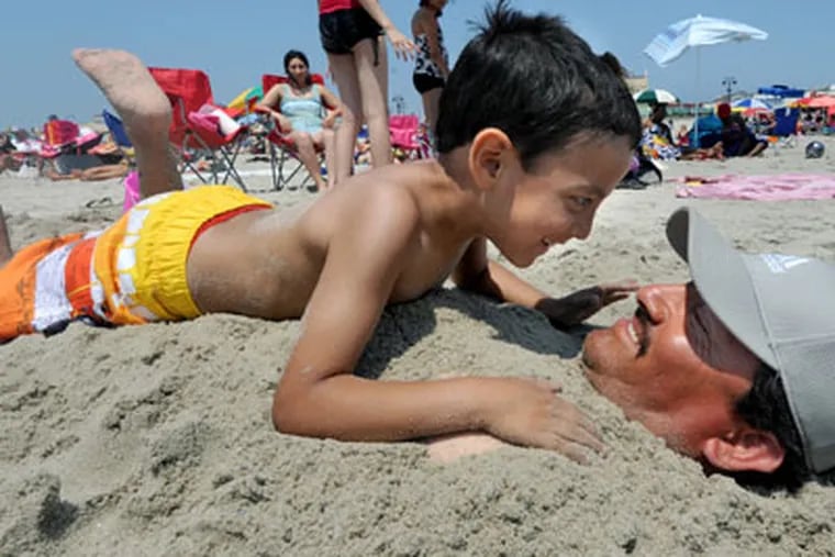 At Ocean City, N.J., beachgoers enjoy Memorial Day on May 28, 2012.   Here, Luis Angel Villa Lobos, 5, gets up close to his dad, Luis Villa Lobos, after he was buried in the sand by friends and family.  They're from Wilmington, DE.  APRIL SAUL / Staff Photographer