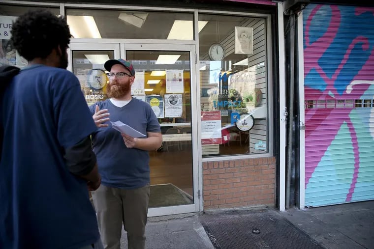Michael Durkin, of the Renegade Company, at right, talks with an unidentified person on Kensington Avenue about a new community work inspired by Ernest Hemingway’s novel “The Old Man and the Sea.”