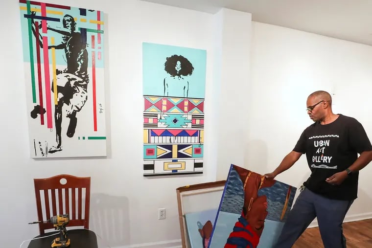 Karl Morris, owner of Urban Art Gallery, arranges pieces by artists Watson Mere and Erice Reid for the Caribbean Creatives Art Show the gallery is hosting.
