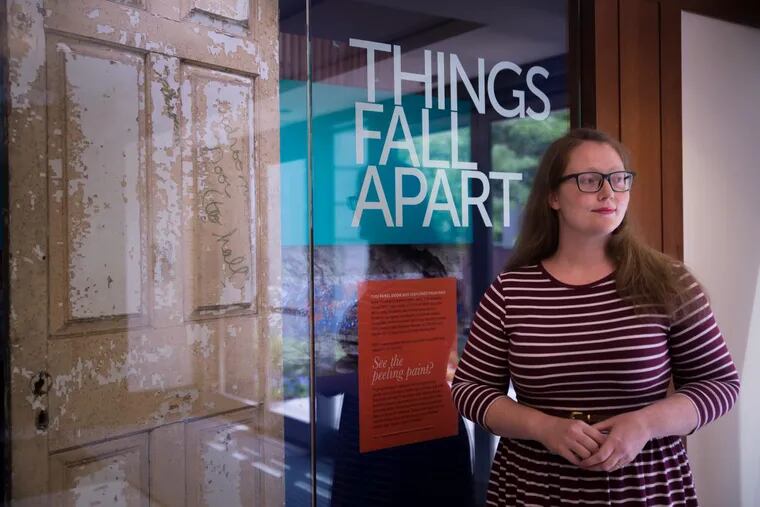 Curator Elisabeth Berry Drago stands next to decaying doorway to exhibit “Things Fall Apart.”