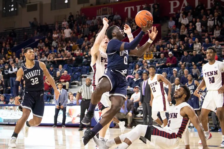 Monmouth's Ray Salnave shoots past Penn's Antonio Woods (ground) for the go-ahead basket in the Hawks' overtime win over the Quakers at the Palestra on Monday.