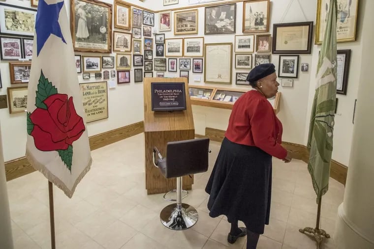 A Father Divine follower, dressed in her Rosebud uniform, walks through one of the many rooms in the Father Divine Museum and Library.