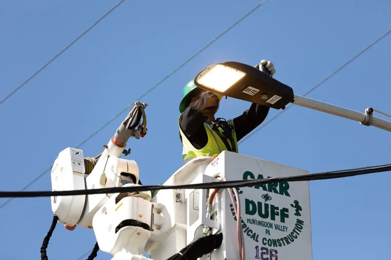 A local crew member tasked with installing new LED street lights across Philadelphia installs a fixture during the 2023 kick-off event for the Philadelphia Street Light Improvement Project.