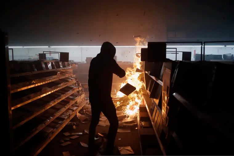 People loot then burn an Office Depot Friday, May 29, 2020, in Minneapolis. Protests continued following the death of George Floyd, who died after being restrained by Minneapolis police officers on Memorial Day.