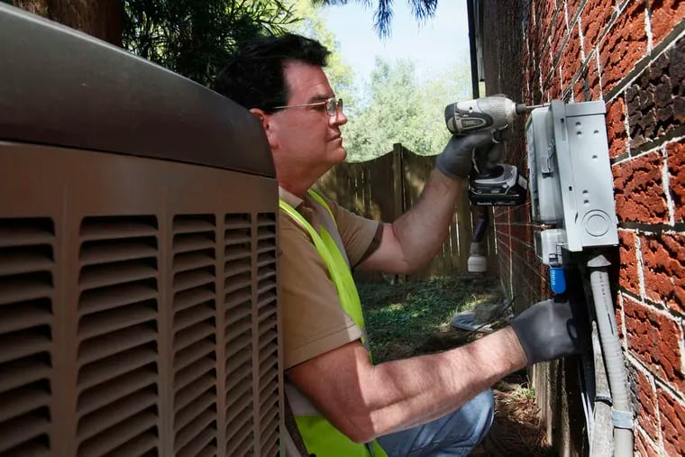 Michael P. King , a Peco field technician, installing a digital cycling unit near a house's central-air unit in 2012. MICHAEL S. WIRTZ / Staff Photographer