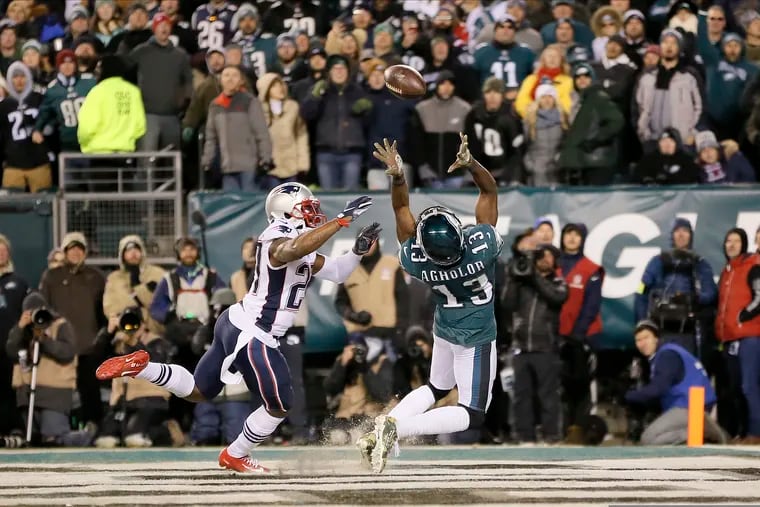 Nelson Agholor reaches back on a fourth-down pass as the Patriots' J.C. Jackson defends. Agholor did not make the play.