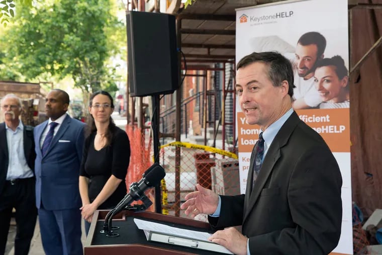 Department of Environmental Protection Secretary John Quigley speaks at a ceremony announcing the relaunch of the Keystone Home Energy Loan Program at the South Philadelphia home of Lizzie Rothwell, who stands with Treasury Secretary Timothy Reese and others.