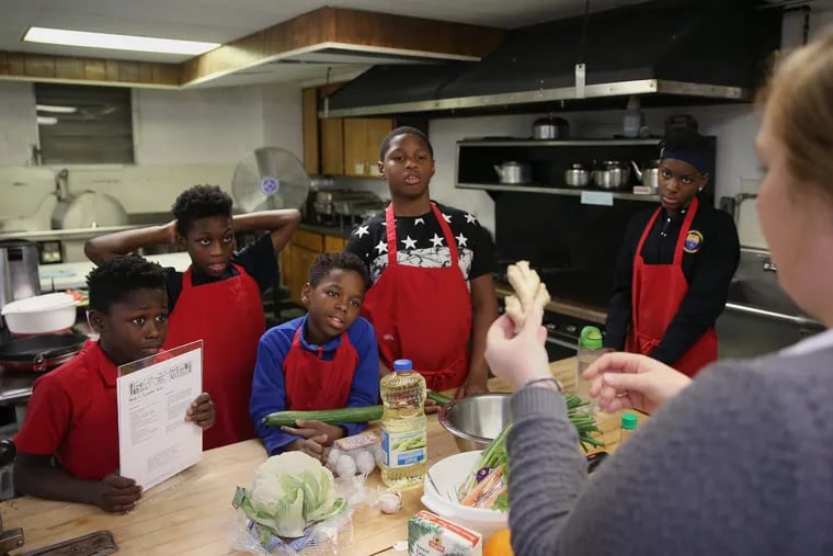 Instructor Maddy Booth, right, shows a piece of ginger root to young chefs (from left) Damir Freeman, 12; Germaine Glover, 10; Kareem Freeman, 11; Shamaj Henry, 10; and Brianna Miller, 12.