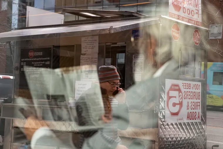 A patron is reflected in the window of Mike's Food Stop food truck, which until last winter was set up on Market Street on Drexel University's campus.