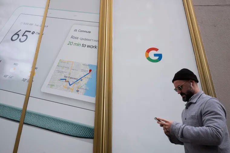 FILE- In this Dec. 17, 2018, file photo a man using a mobile phone walks past Google offices in New York. (AP Photo/Mark Lennihan, File)