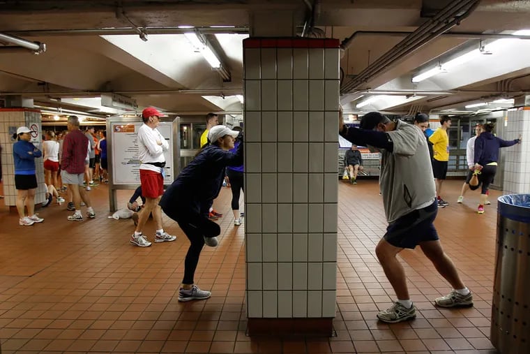 Courtney Chambers (left) and her father, Ed Sullivan (right) stretch in the Olney subway station before the start of the 2013 Blue Cross Broad Street Run in Philadelphia.