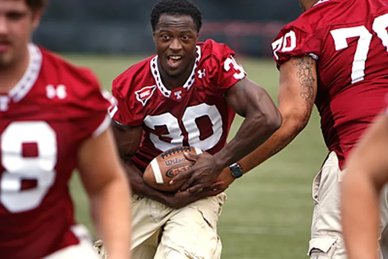 Bernard Pierce, center, takes a hand-off at the training facility on Temple's main campus. (David Maialetti / Staff Photographer)