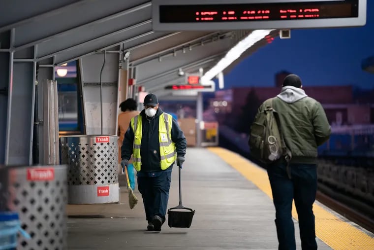 SEPTA worker Ervin Lavenhouse wears a mask as he sweeps up trash on the platform at the 52nd Street station in Philadelphia on March 18, 2020. SEPTA employees are among the essential workers who have sounded the alarm about dangerous working conditions during the coronavirus pandemic.