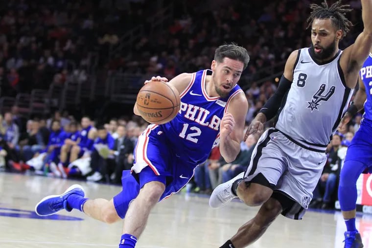 T. J. McConnell, left, of the Sixers drives to the basket against Patty Mills of the Spurs during the first quarter at the Wells Fargo Center on Jan 3, 2018.