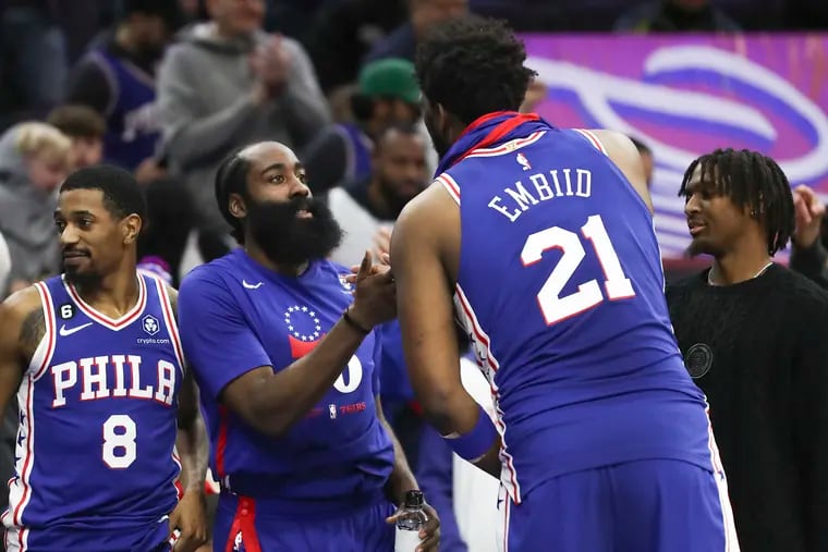 Sixers guard James Harden and center Joel Embiid high-five on the bench after a win against the Detroit Pistons at the Wells Fargo Center.