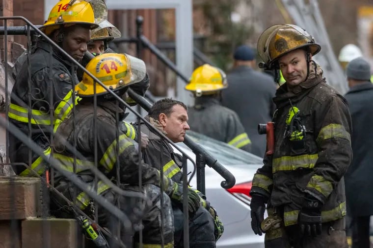 Fire fighters sit on steps near fire scene were 12 people have died. Philadelphia fire department at rowhouse fire on N. 23rd near Ogden Street on Wednesday morning January 5, 2022.