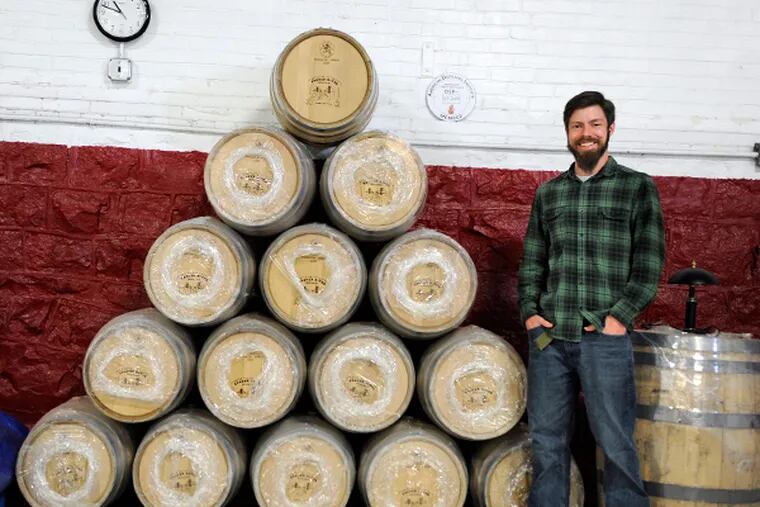 James Yoakum poses with his still-unopened 15-gallon American oak barrels that he will soon use for aging his bourbon and rye whiskey. Three years after setting up shop in Camden, he has the license required to start production in the city's first distillery since prohibition. (TOM GRALISH/Staff Photographer)
