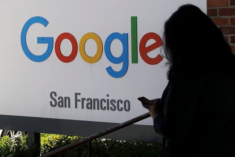 In this May 1, 2019, photo, a woman walks past a Google sign in San Francisco. Google is snooping on billions of people. (AP Photo/Jeff Chiu, File)