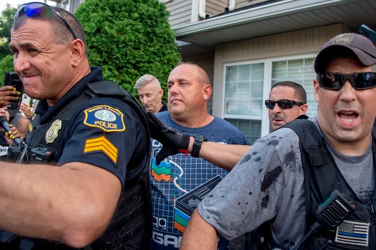 Police escort Edward Cagney Mathews through a crowd of protesters earlier this month. Protesters gathered outside his Mt. Laurel home after a video went viral on social media that allegedly showed Mathews shouting racial slurs and offensive language at his neighbors.
