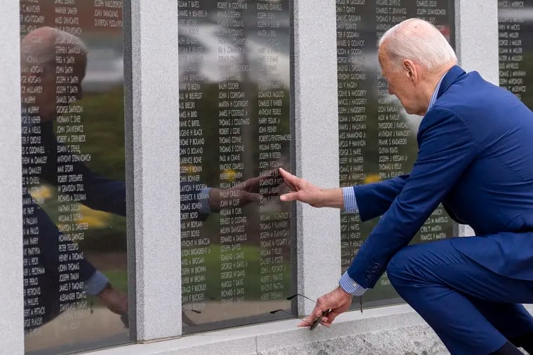President Joe Biden reaches to touch the name of his uncle Ambrose J. Finnegan, Jr., on a wall at a Scranton war memorial on Wednesday in Scranton.