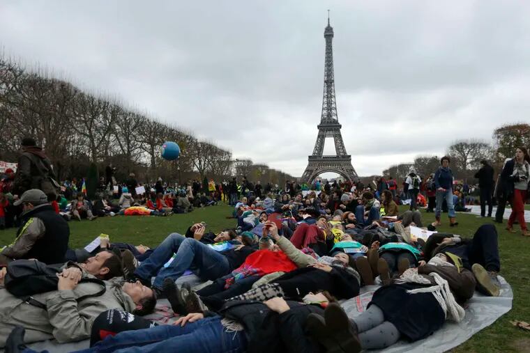 With the Eiffel Tower as a backdrop , activists stage a die-in to call attention to populations threatened by climate change. MATT DUNHAM / AP