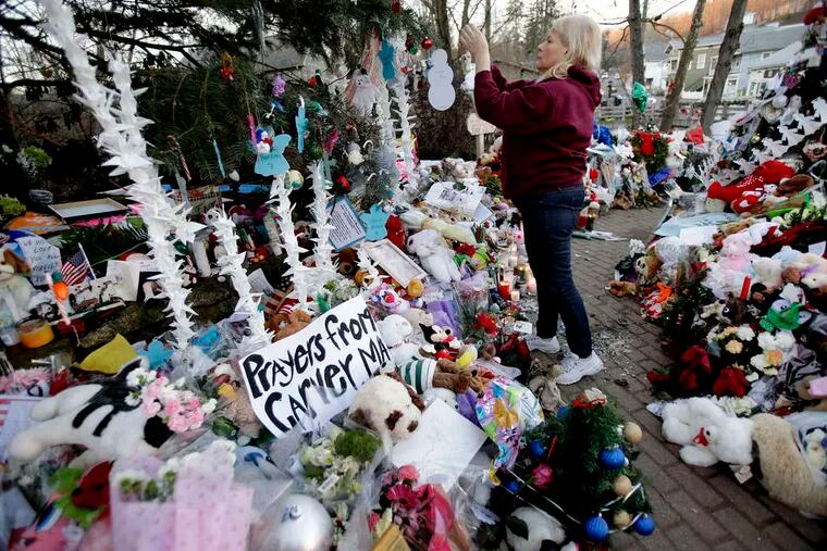 Nancy Hotchkiss of Naugatuck, Conn. , adding to a memorial six days after the 2012 Sandy Hook Elementary School killings. Some of the mementos were turned into recycled material. SETH WENIG / Associated Press