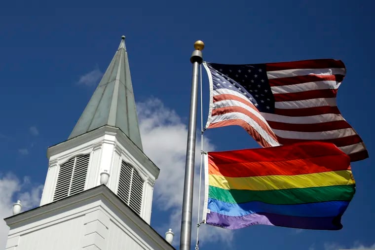 A gay pride rainbow flag flies along with the U.S. flag in front of the Asbury United Methodist Church in Prairie Village, Kan., on Friday, April 19, 2019.
