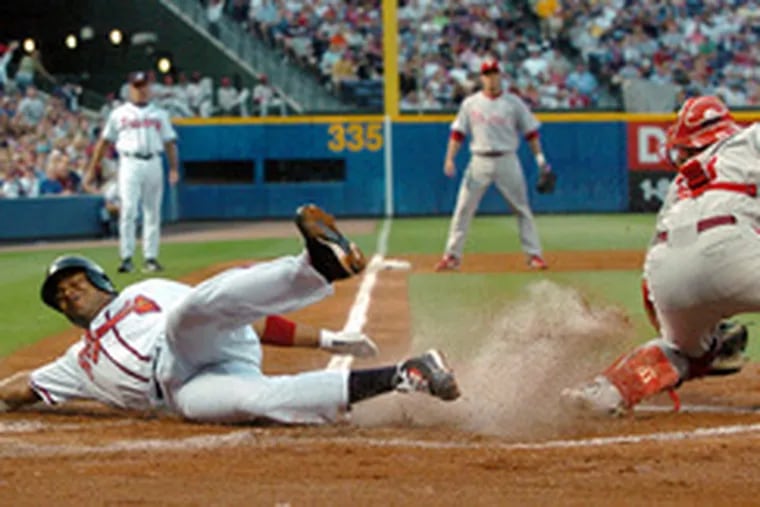 Braves&#0039; Andruw Jones slides home to score against Phillies catcher Carlos Ruiz in the second inning.
