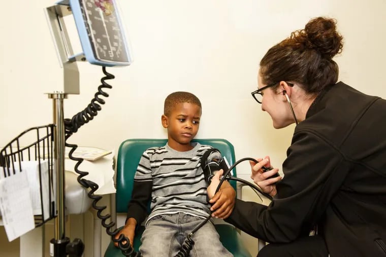 Five-year-old Sha-Zere Jackson, center, has his blood pressure checked by Dr. Laura Deutsch, a 3rd year Pediatric Resident at Cooper Hospital, in Camden, New Jersey.