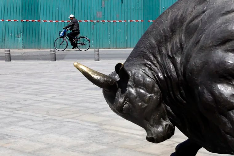 A man cycles past a statue of a bull in Beijing on Monday.