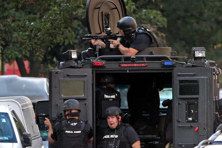 Heavily armed police are stationed inside a SWAT vehicle outside the scene at 15th Street and Erie Avenue August 14, 2019, where a gunman was holed up after six police officers were shot in a confrontation with gunmen in the Tioga section of North Philadelphia. The Philadelphia Police Foundation said it helped pay for the rifles used by SWAT officers during that standoff.