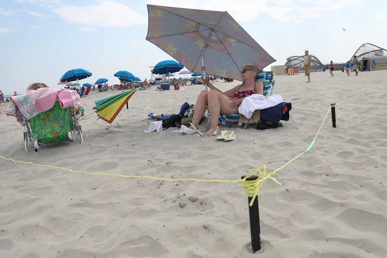 Peggy Kane (right) of Philadelphia, and her sister-in-law, Carol Kane of Cinnaminson, N.J., enjoy the beach after putting up string to maintain their distance from others in Wildwood, N.J., on Friday, July 3, 2020. Peggy Kane said she got the idea from a friend and decided to try it out Friday. The two are spending time at their summer home in Wildwood.