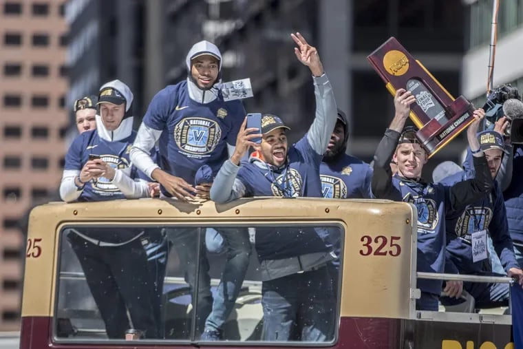 Villanova’s Mikal Bridges, left of center, and Phil Booth, center, and their teammates react to the crowd at City Hall as their bus travels down Market Street during the celebration parade held  for the team on Thursday.