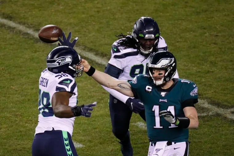 Quarterback Carson Wentz gets a pass off before being hit by Seattle's Rasheem Green and Ezekiel Ansah in the Eagles' playoff loss in January.