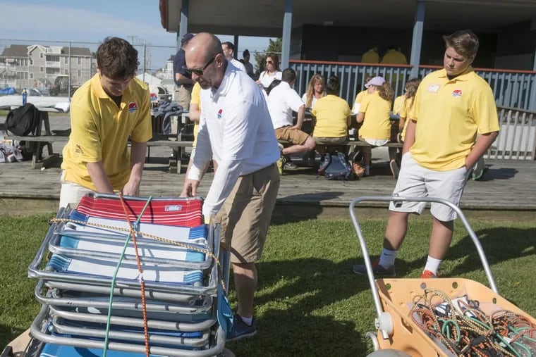 At a training camp for Beach Caddy caddies at Sandcastle Park in Ocean City on Memorial Day weekend, Patrick Kelly (right) watches as co-owner Jeff Yeakel, a physical education teacher from Souderton, instructs Nick Lattanze,on the best way to stack beach gear on a cart. ED HILLE / Staff Photographer.