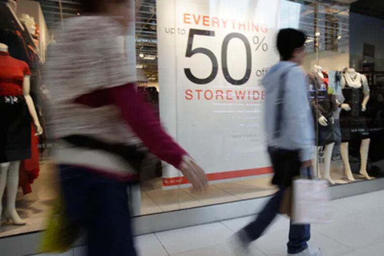 In this Nov. 9, 2011 photo, shoppers walk past a sale sign at the New York & Company outlet store while shopping at Dolphin Mall, in Miami.  (AP Photo/Lynne Sladky)
