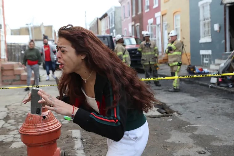 An unidentified woman reacts at the scene of a fatal fire on the 3200 block of Hartville Street in Philadelphia on Sunday. Derek Bowmer, the executive officer of the Philadelphia Fire Department, said three juveniles and one adult male are dead as a result of the fire.