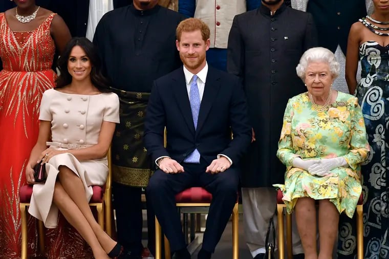 In this Tuesday, 2018 file photo Britain's Queen Elizabeth, Prince Harry and Meghan, Duchess of Sussex pose for a group photo at the Queen's Young Leaders Awards Ceremony at Buckingham Palace in London. In a stunning declaration, Britain's Prince Harry and his wife, Meghan, said they are planning "to step back" as senior members of the royal family and "work to become financially independent."
