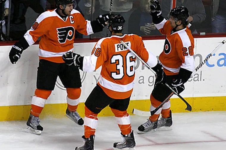 Mike Richards, left, celebrates with Darroll Powe and Claude Giroux after he scored a goal. (AP Photo/H. Rumph, Jr.)