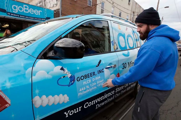 GoPuff.com's Simon Ilishayev places a state Liquor Control Board magnet on the side of a delivery car, signaling the service has state approval to make beer deliveries.