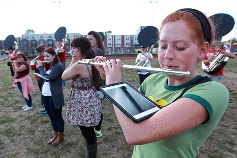 Temple Band flutist Johanna Wiley looks down at her iPad to see the sheet music for the music she is playing during practice on Wednesday. ( MICHAEL BRYANT / Staff Photographer )