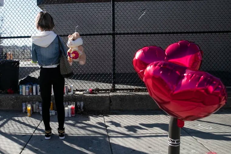 A close family friend who did not wish to be identified places a candle at the memorial for 12-year-old Thomas "TJ" Siderio Jr. near 18th and Barbara Streets in South Philadelphia.