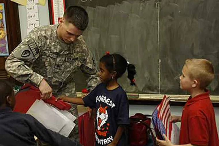 Sgt. Glenn Devitt Jr. receives class letters attached to paper flags from Maryam Hamdaza (center) and John Sullick (right) representing Mrs. Bloch's first grade class. (Michael S. Wirtz / Inquirer).