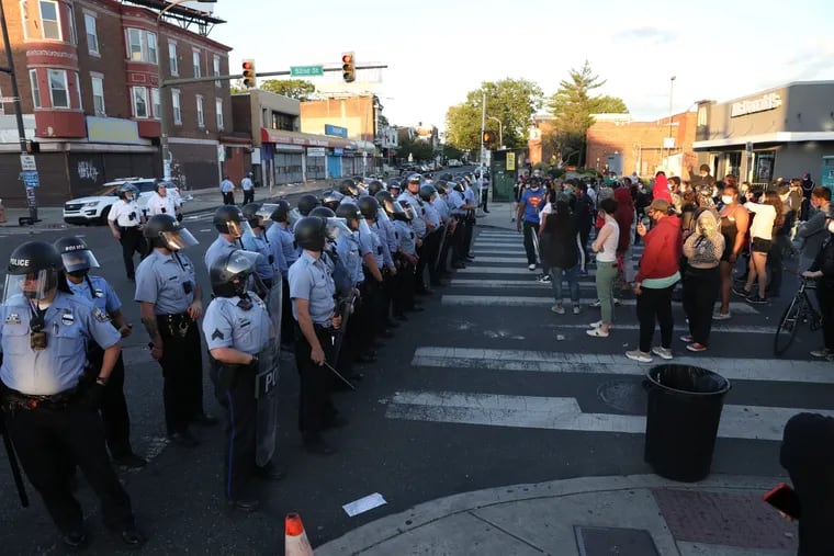 A line of riot police face off with a group of several dozen protesters and 52nd and Chestnut streets in Philadelphia on Sunday, May 31, 2020.