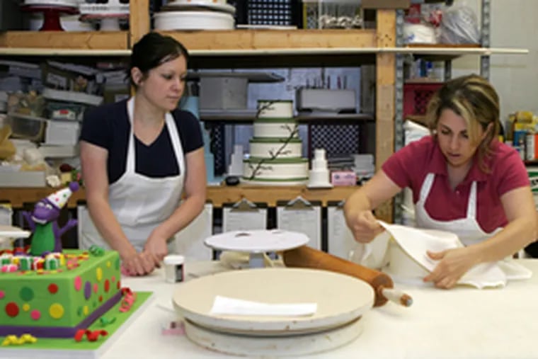 Cake designer Heather Smith (left) and Nina Asadoorian work on a confection for a client at Rilling&#0039;s Bakery.